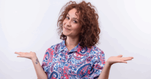 Mulher vestindo uma camisa de gola, a camisa é colorida e a mulher tem cabelo ruívo.