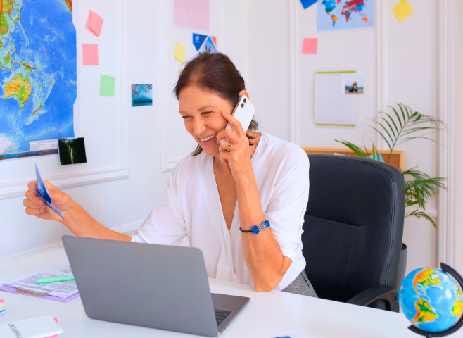 Mulher sentada no escritório de uma escola de inglês com um panfleto na mão e ao telefone.